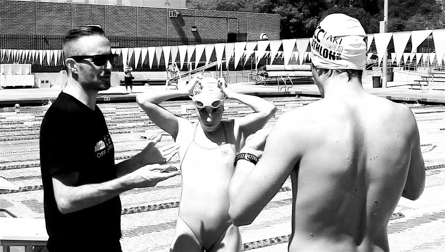 Gareth Thomas coaching two swimmers on the pool deck